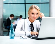 Portrait of beautiful woman using laptop at her workplace on the background of business people